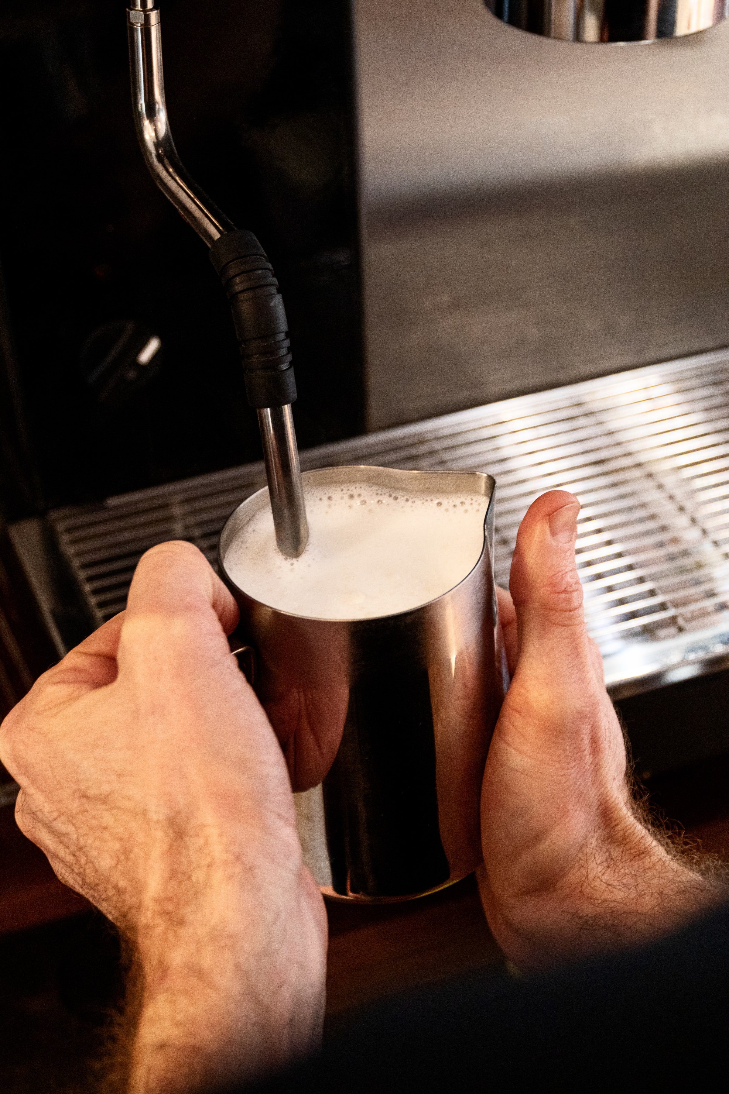 Unas manos preperando lecho para un café ; A pair of hands preparing milk for a coffee